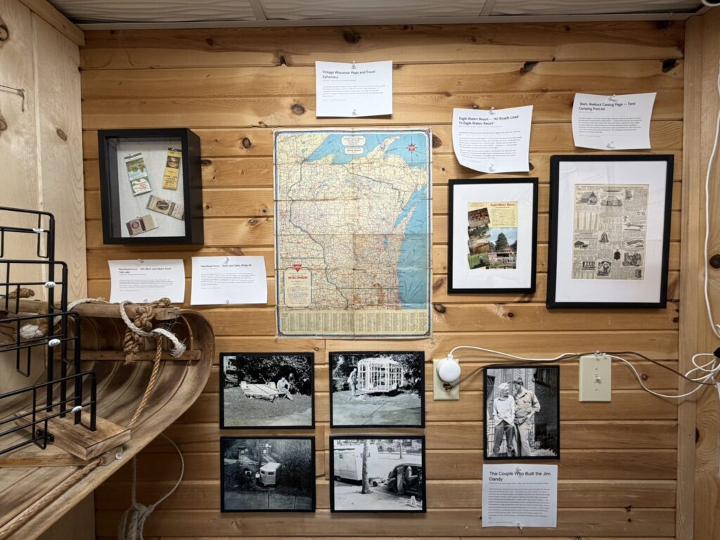 Wood-paneled wall display with a large Wisconsin map at center, flanked by framed photos and printed notes.